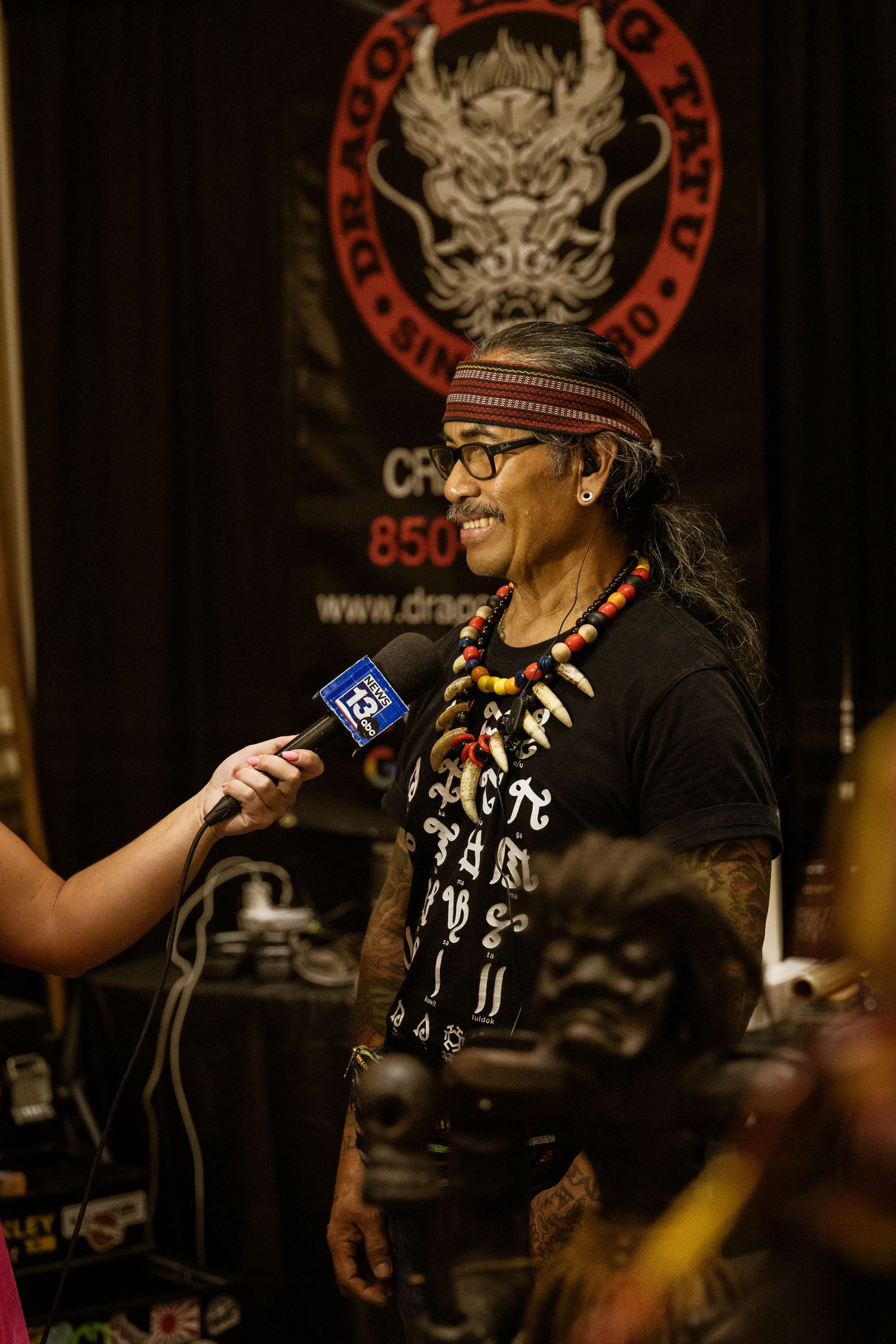 Radio interview setup at a tattoo convention with branded backdrop.