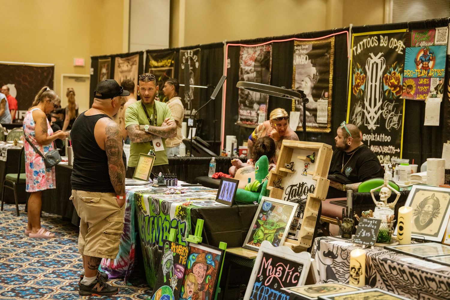 Convention hall with rows of vendor booths displaying artwork and merchandise.