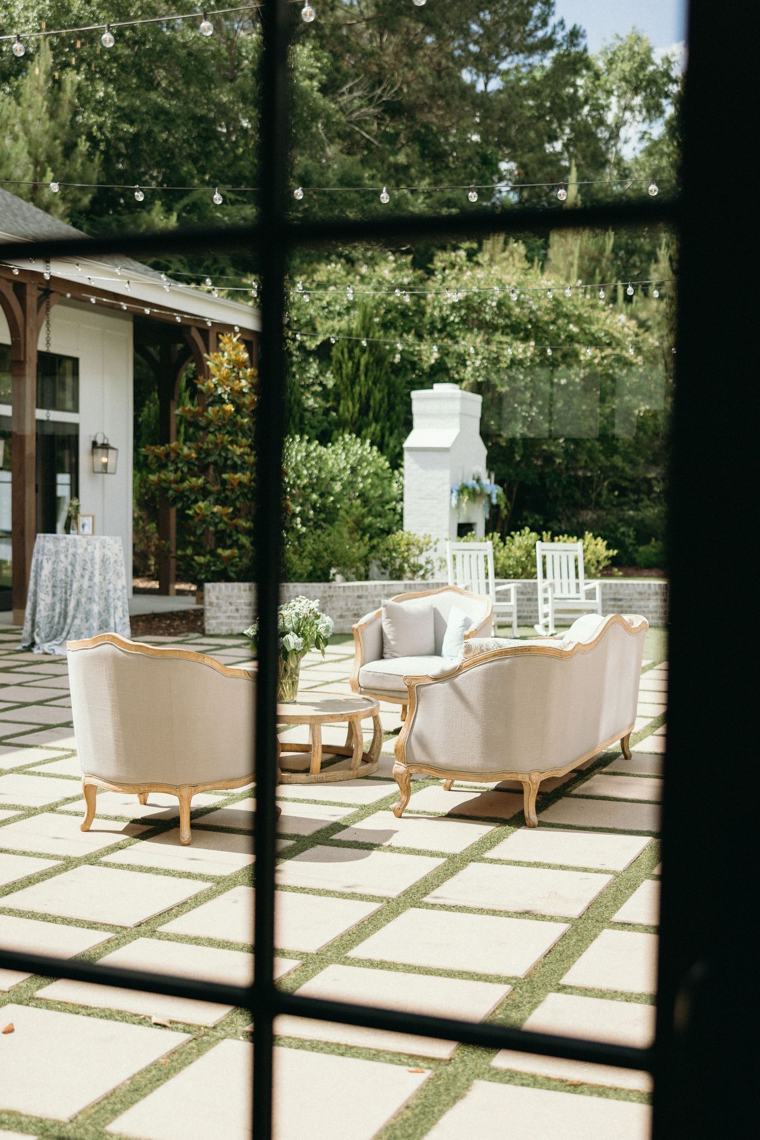 Elegant white outdoor patio furniture arranged on stone pavers viewed through window. The Bradford, Separk  Mansion, Graylyn Estate