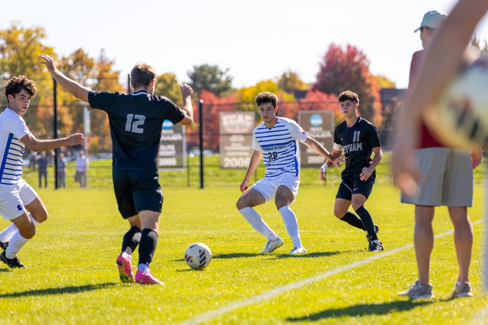 Youth soccer players compete in match on grass field during fall season.