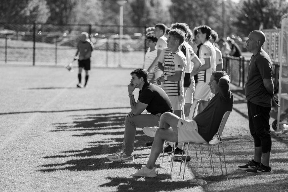 Spectators watch from sidelines during outdoor sporting event in black and white photograph.