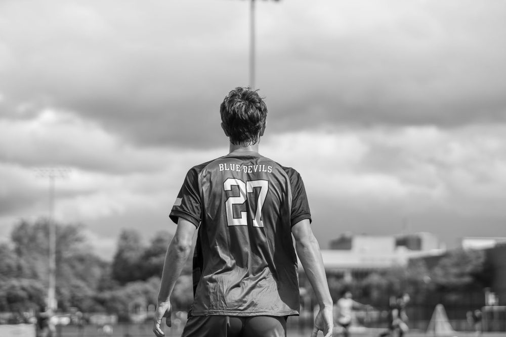 Back view of soccer player wearing jersey number 27 against stormy sky.