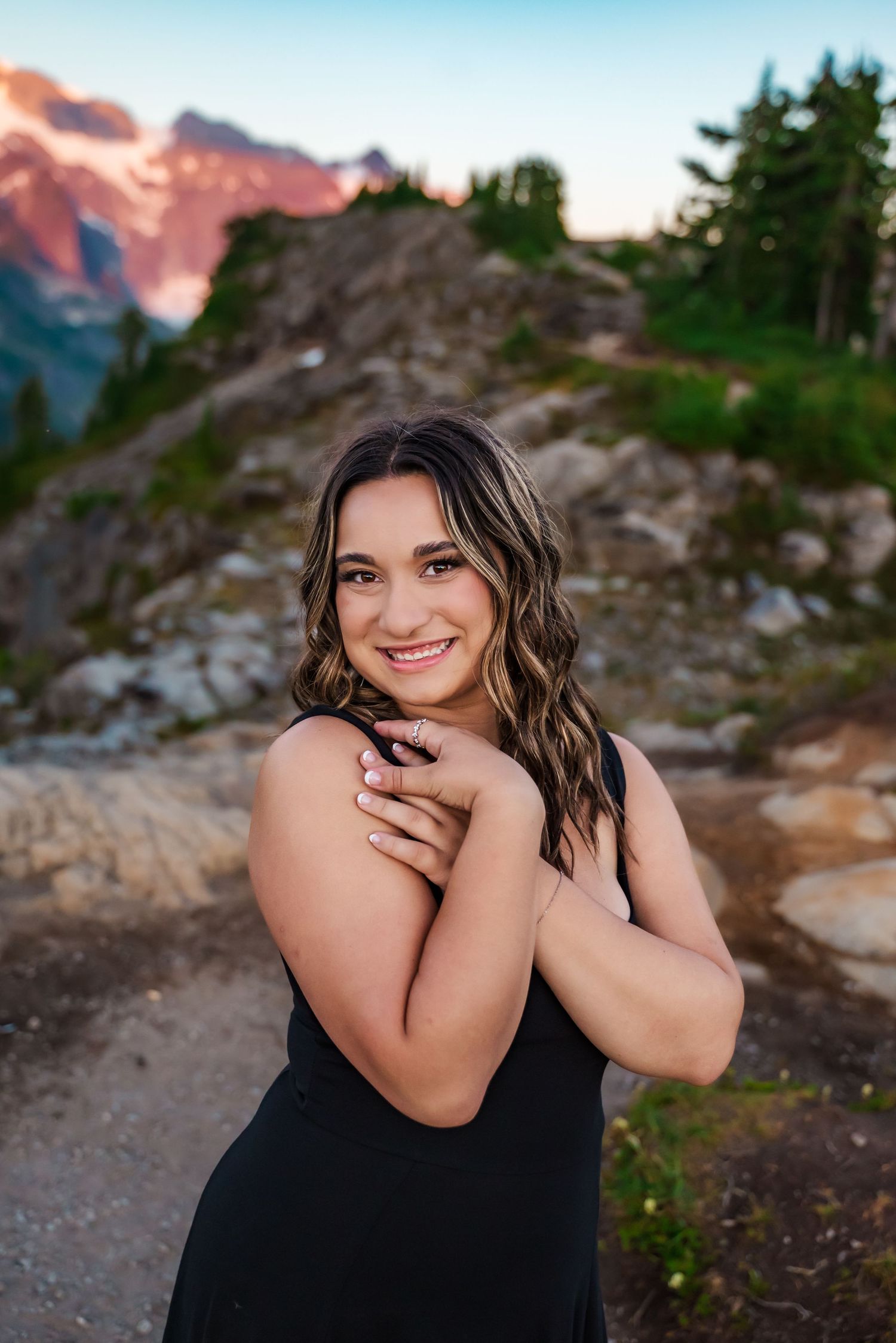 senior girl poses in front of reflective water at artist's point backed by mt shuksan