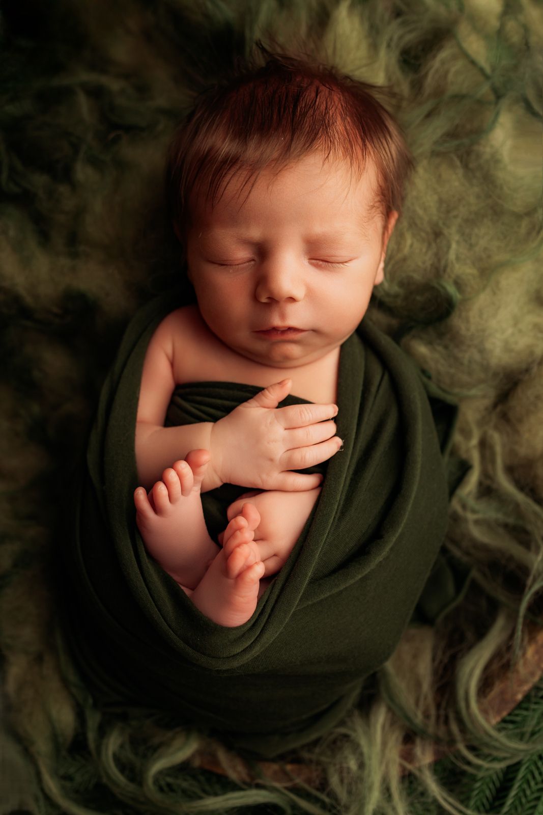 Sleeping newborn in floral outfit during professional studio photography session.