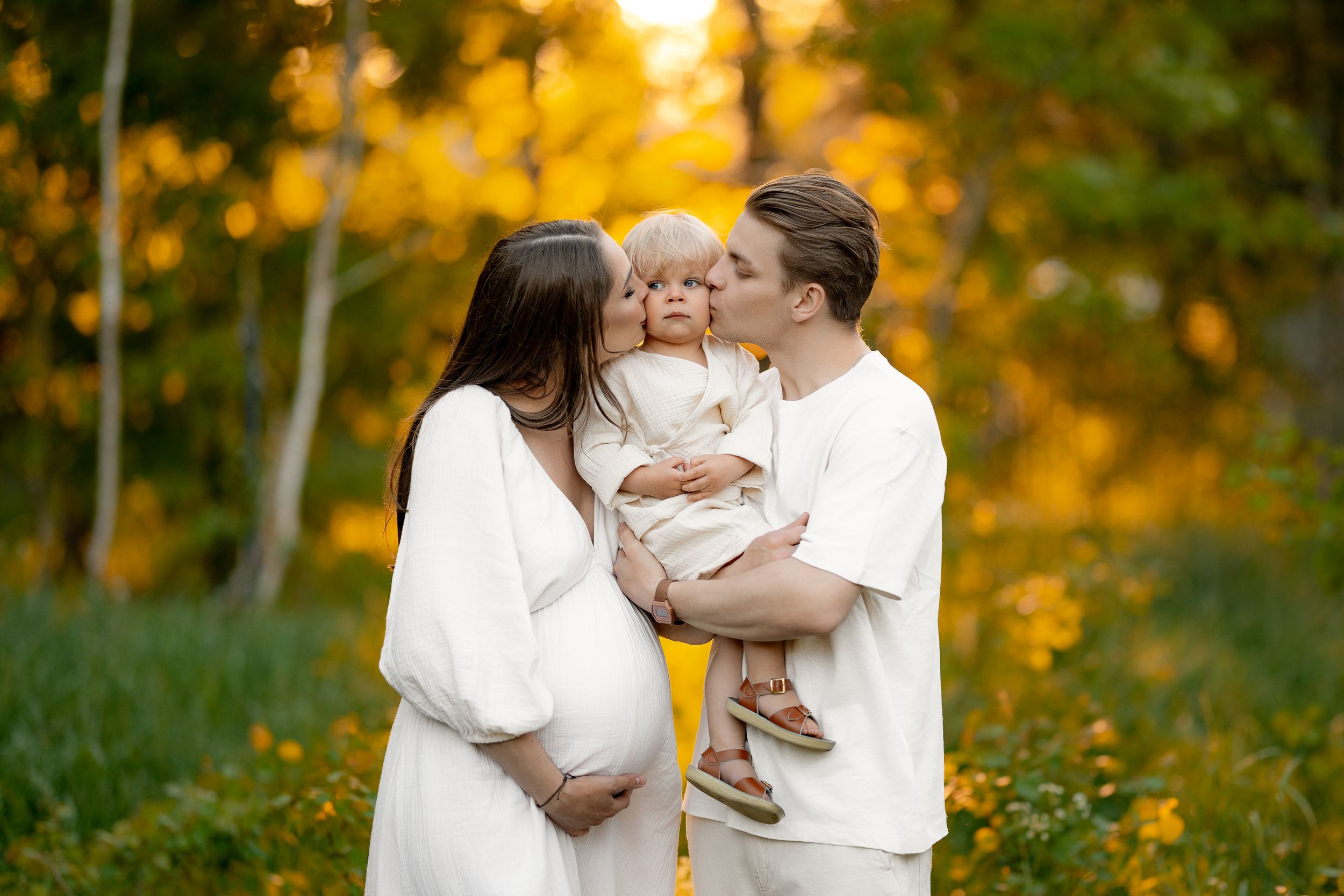 Family portrait at sunset with fall foliage creating a golden backdrop.