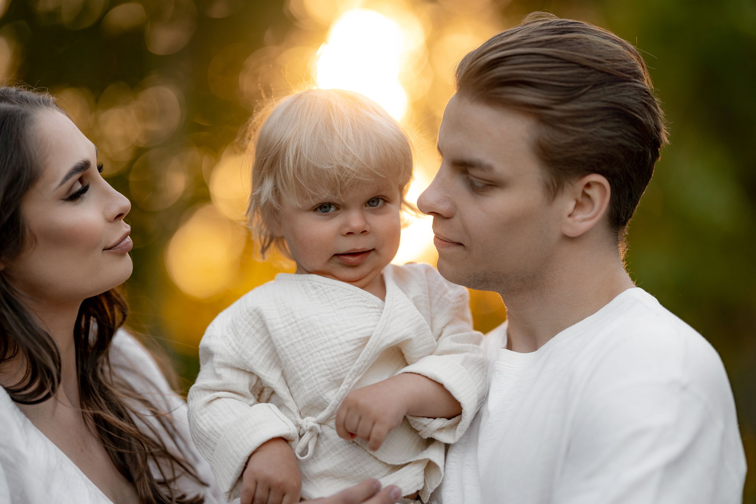Sweet family moment captured against autumn trees at golden hour.
