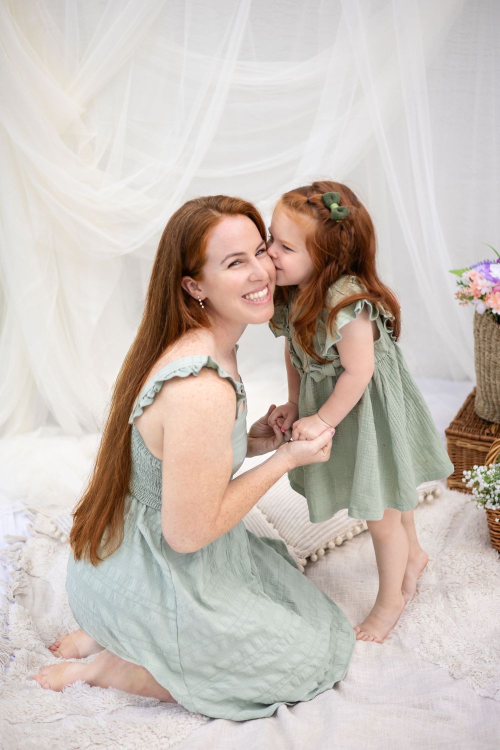 A sweet moment between parent and child wearing matching mint green dresses against white backdrop.