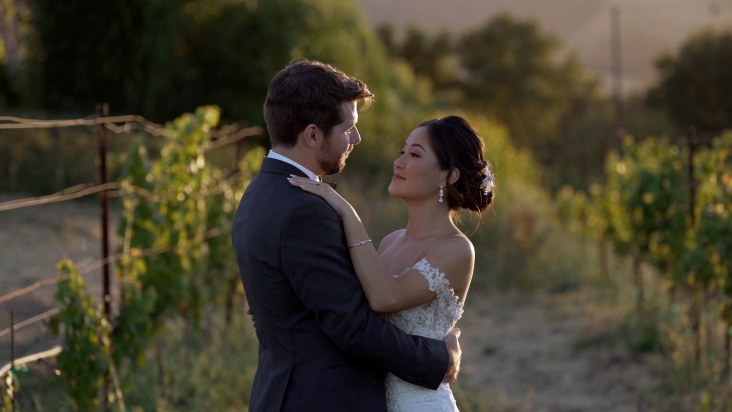 A bride and groom share an intimate moment during their outdoor wedding photoshoot in formal attire.