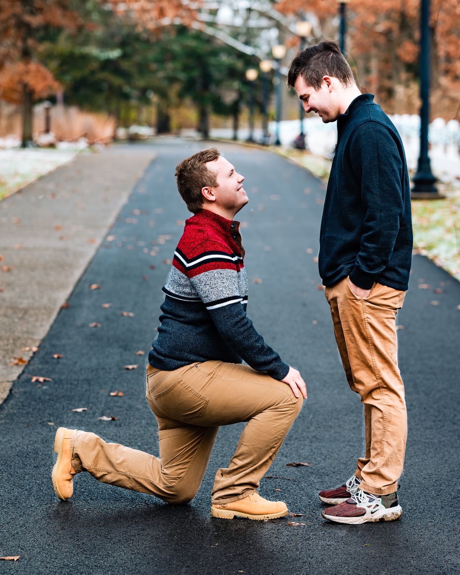 A sequence of someone proposing on a path covered in fall leaves.