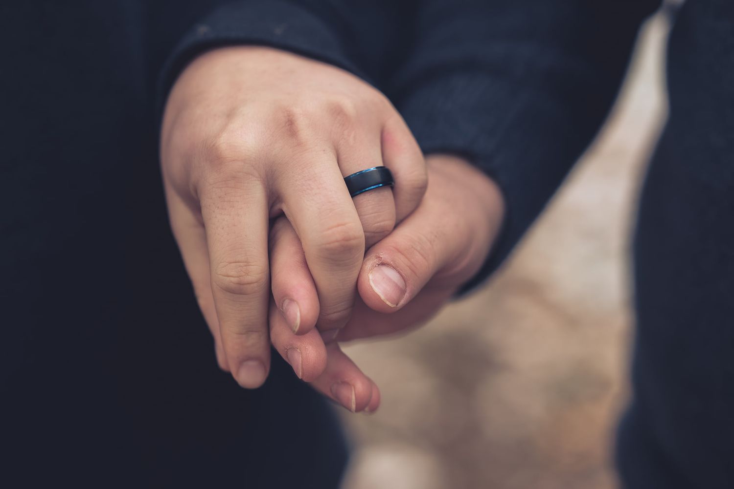 Close-up detail of hands clasped together in an intimate moment.