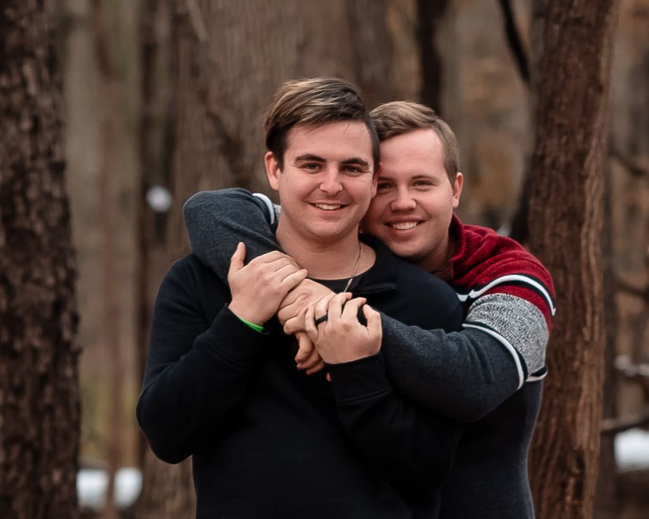 Two people share an intimate embrace among autumn trees.