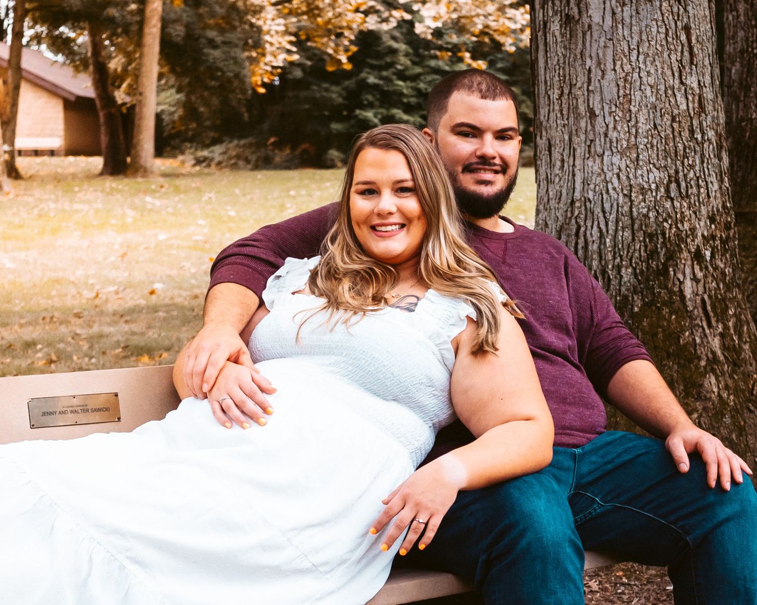 A couple sitting together on wooden steps during an autumn engagement photoshoot.