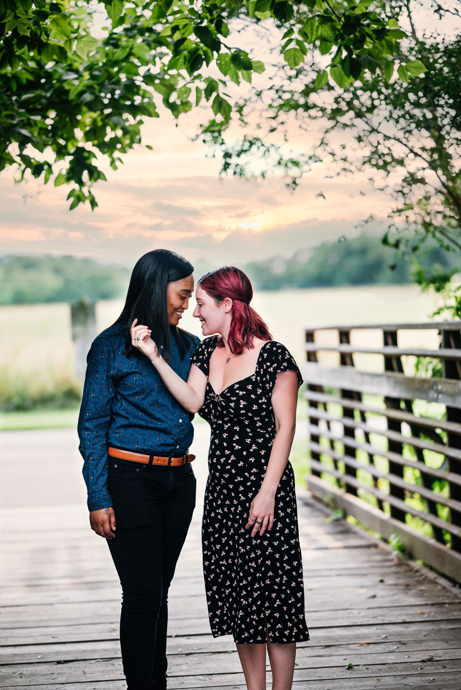 Couple in casual attire sharing tender moment on wooden boardwalk at sunset.