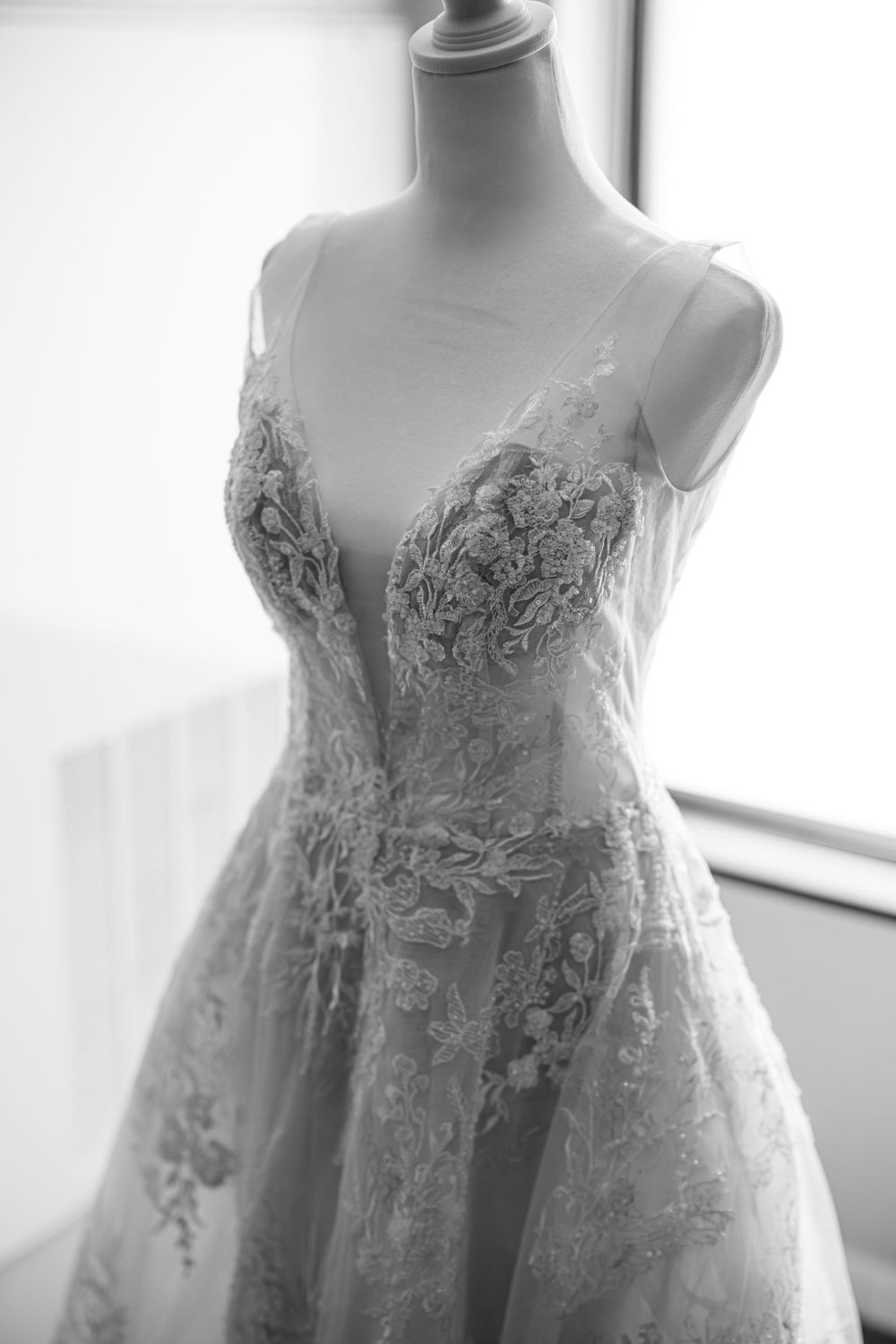 Elegant lace wedding dress details shown on mannequin in soft natural light.