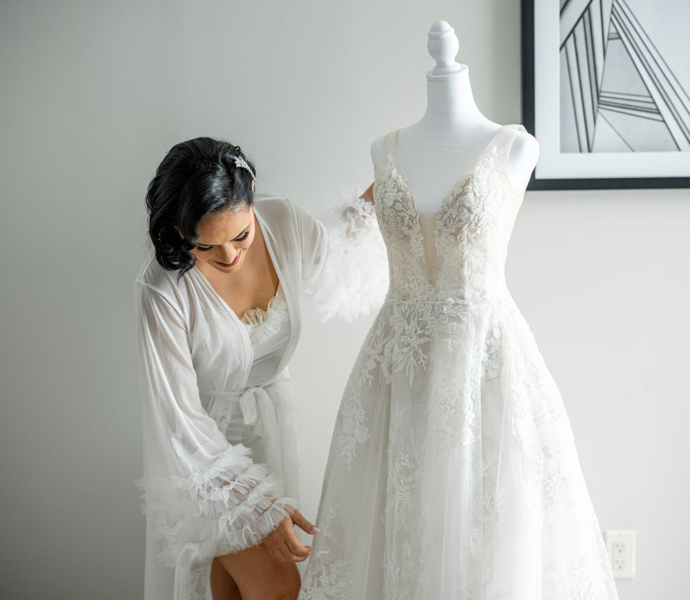 Wedding dress displayed on mannequin with delicate lace details in bright studio setting.