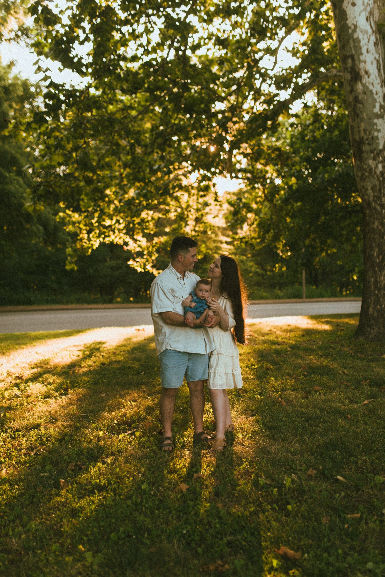 Couple shares romantic moment in summer evening light beneath tree canopy.