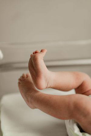 Close-up of tiny newborn baby feet and legs in hospital bassinet.
