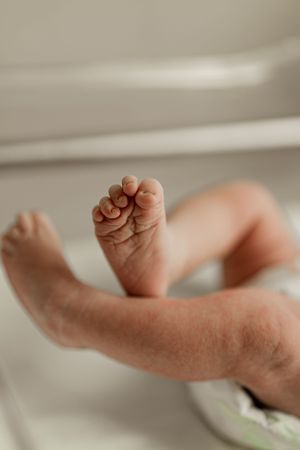 Detailed close-up of newborn baby toes and feet in hospital nursery.