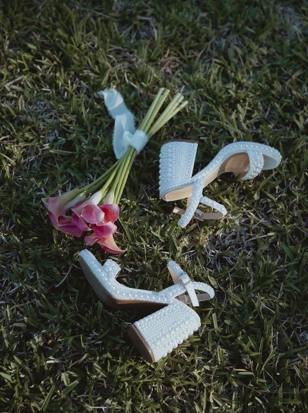 A close-up montage of delicate handmade crochet baby booties in light blue and pink laid on green grass.