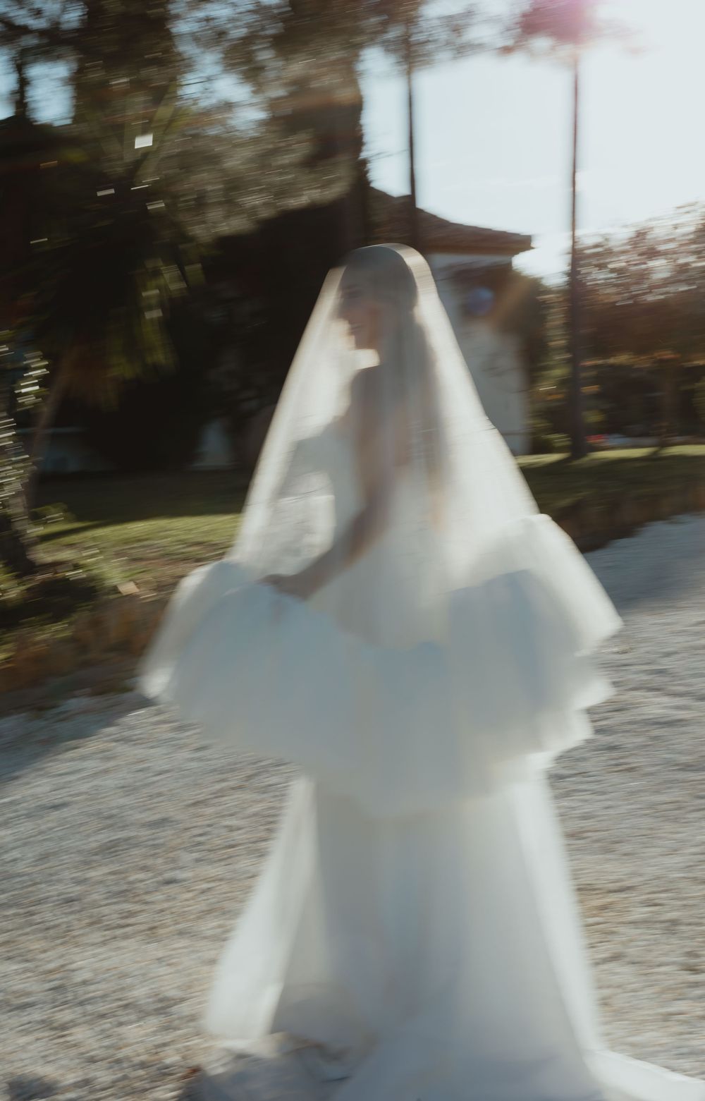 A flowing white wedding dress catches the sunlight while twirling on an outdoor patio.