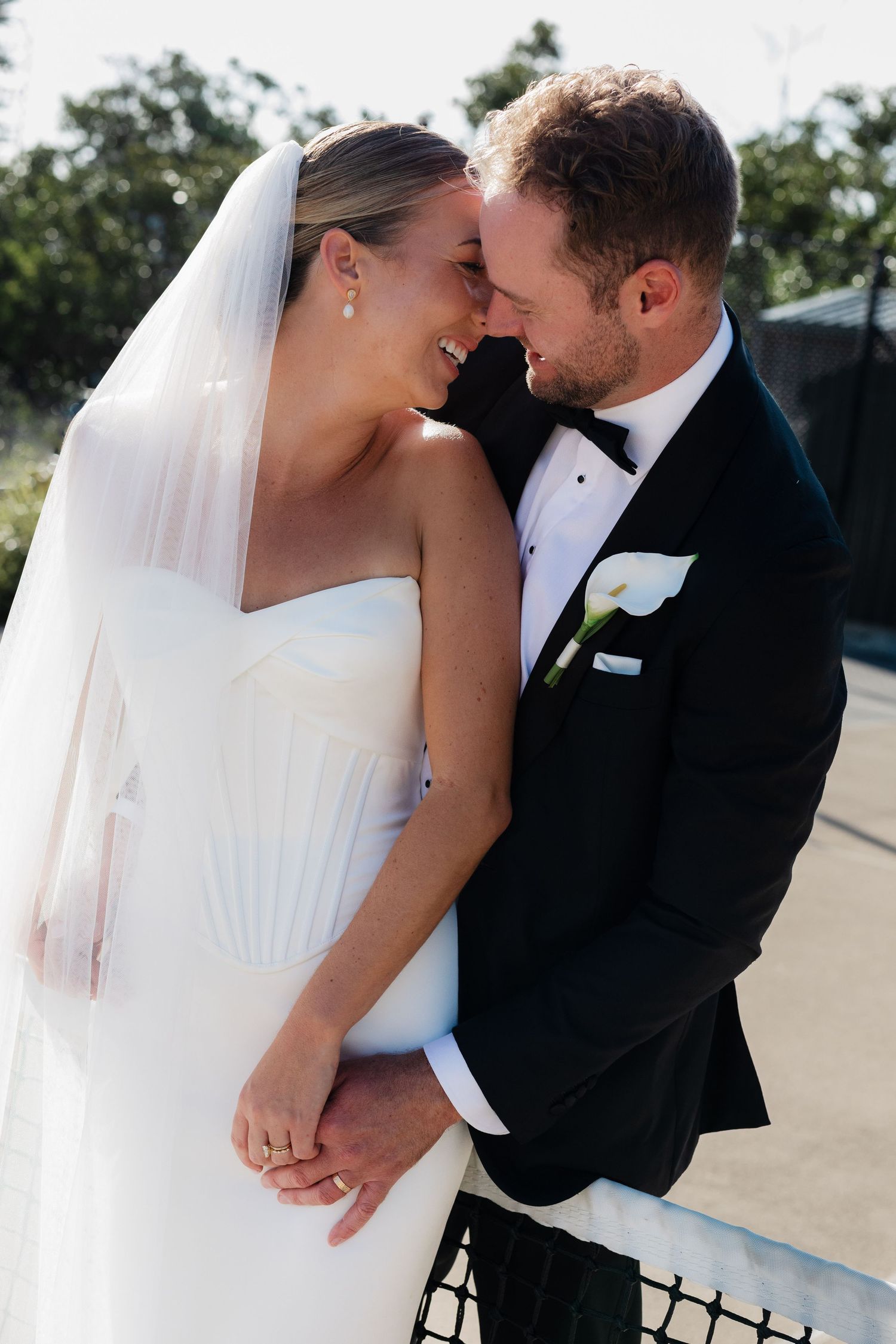 Wedding couple sharing intimate moment by window in minimalist white room.