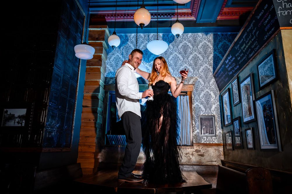 Couple silhouetted against blue-lit architectural backdrop with vintage lanterns.