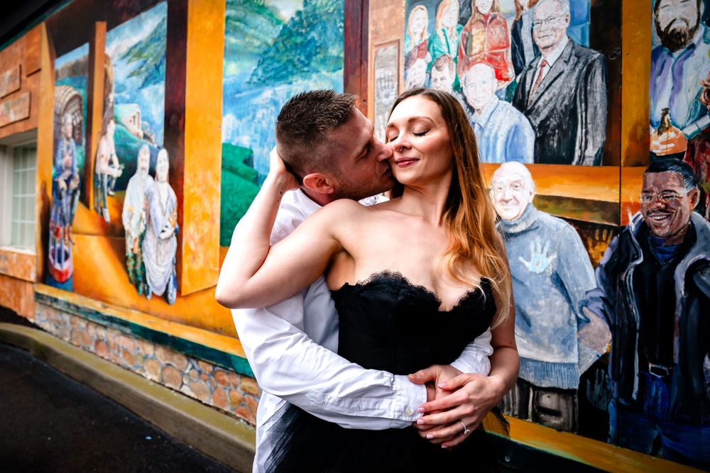 A romantic moment shared against a vibrant mural wall backdrop.