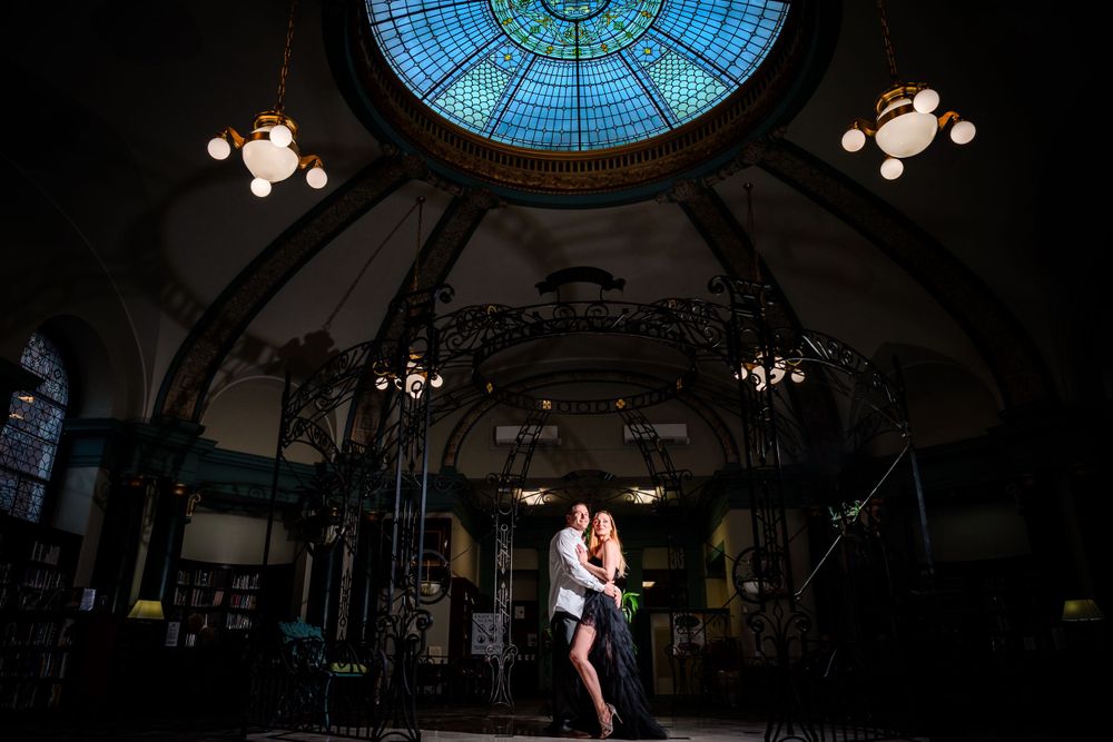 A romantic moment under a grand domed ceiling with stained glass and chandelier lighting.