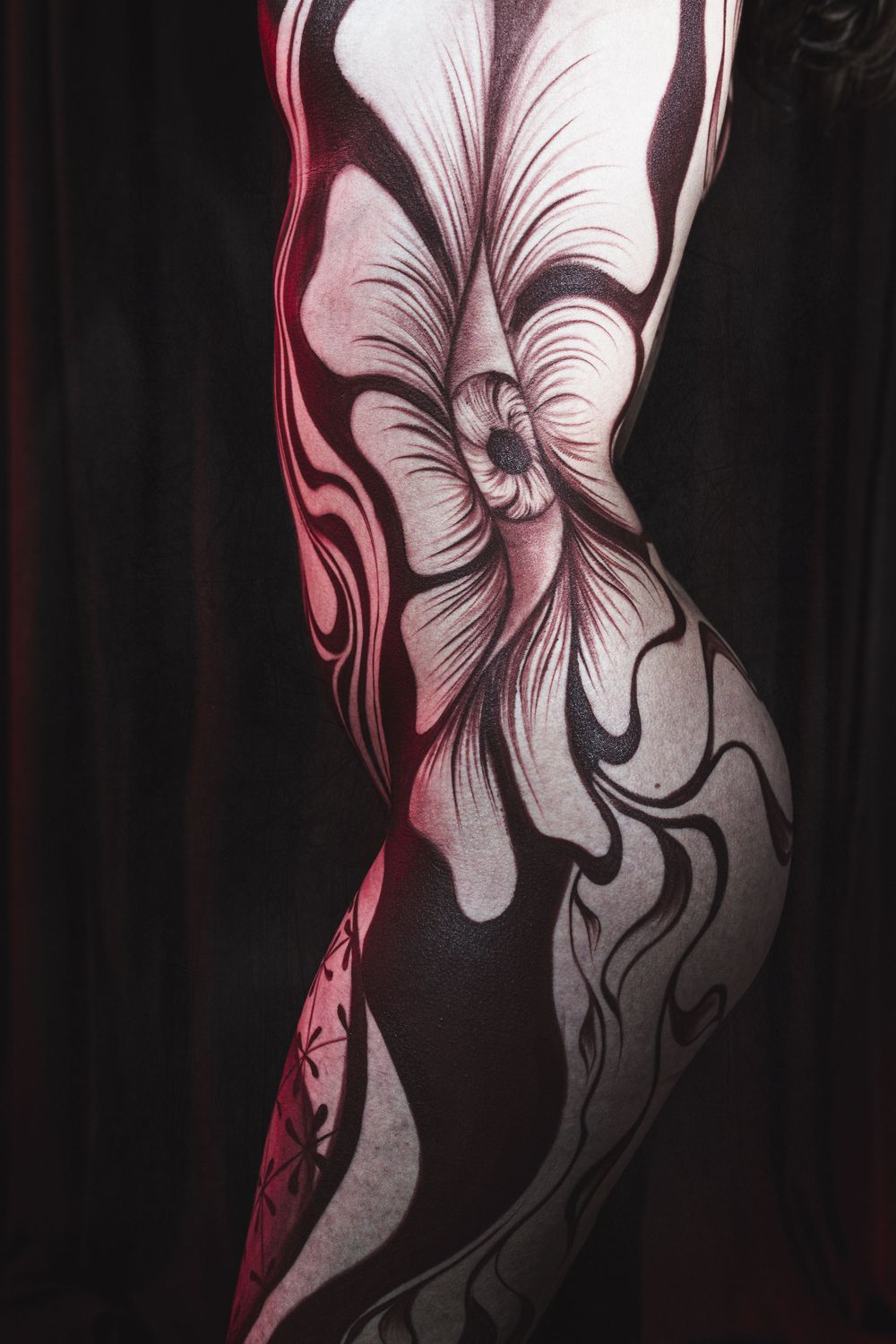 Close-up of detailed floral body paint artwork in black and white on female torso.