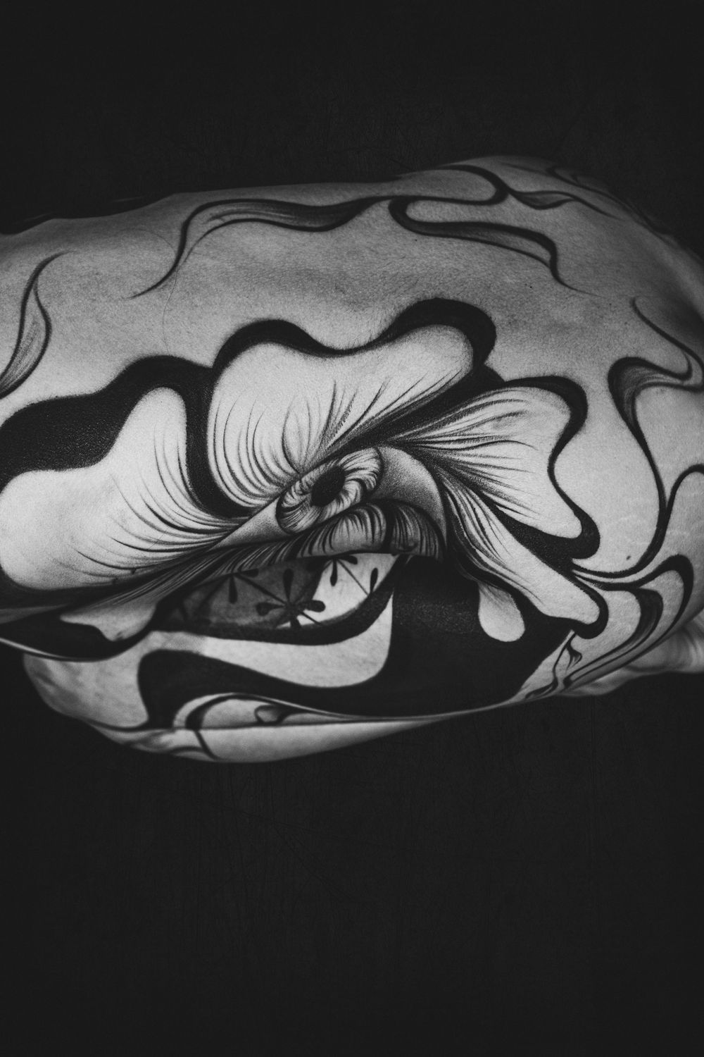 Black and white close-up of detailed eye body paint design on clenched fist.