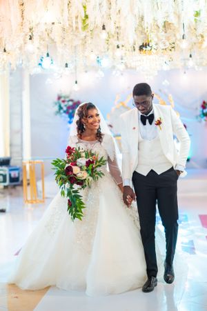 Wedding couple walks through an elegant venue with white decor and falling confetti.
