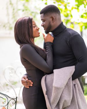 A couple shares an intimate moment together while wearing dark formal attire.