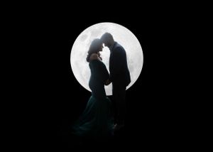Romantic silhouette of a couple embracing against a full moon backdrop.