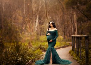 Maternity portrait in teal off-shoulder gown with dramatic train on woodland boardwalk.