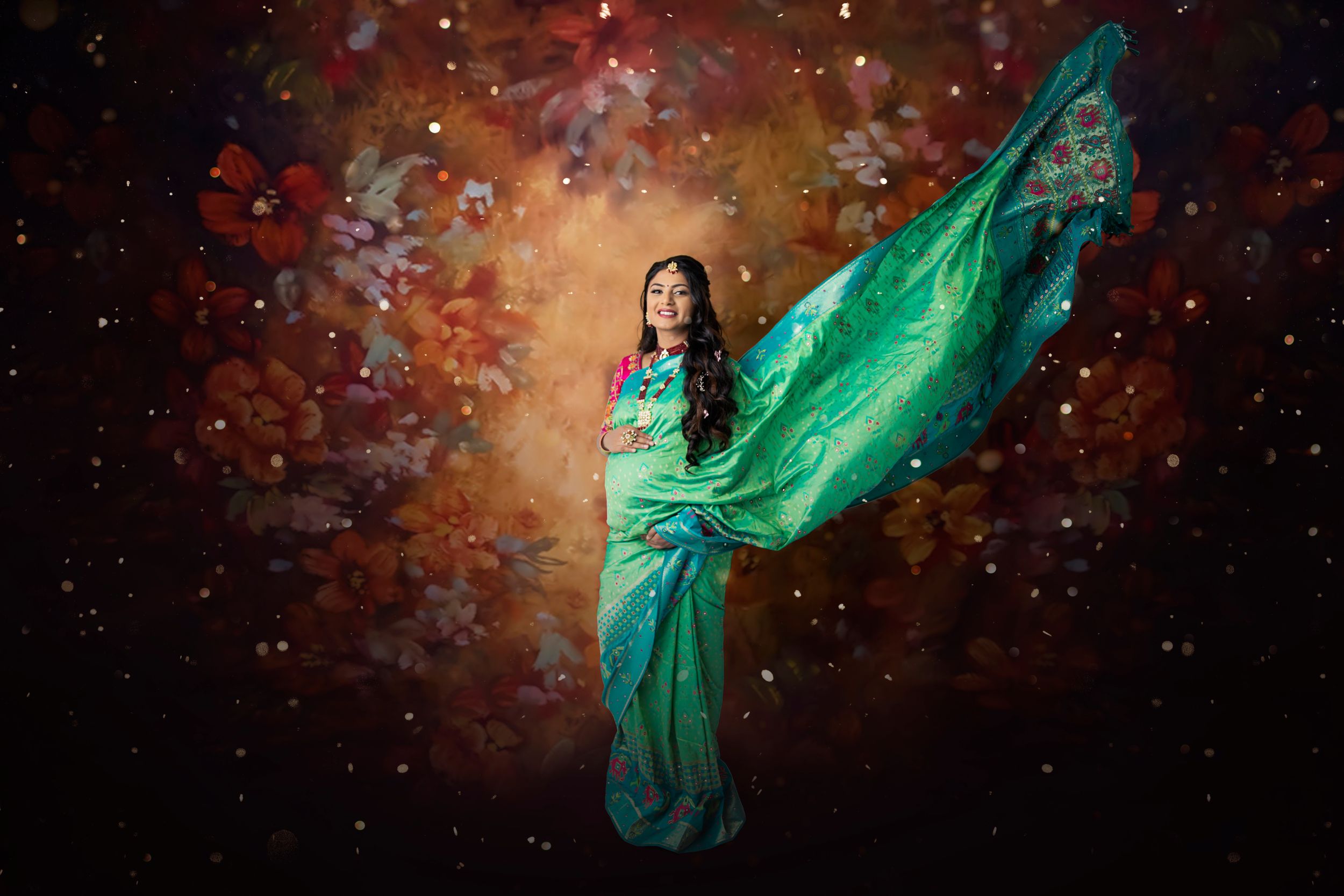 Woman in flowing green sari poses against a magical starry background with floating fabric.