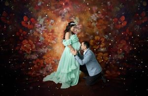 Romantic maternity photo of couple against cosmic backdrop with teal dress and glowing bokeh effects.