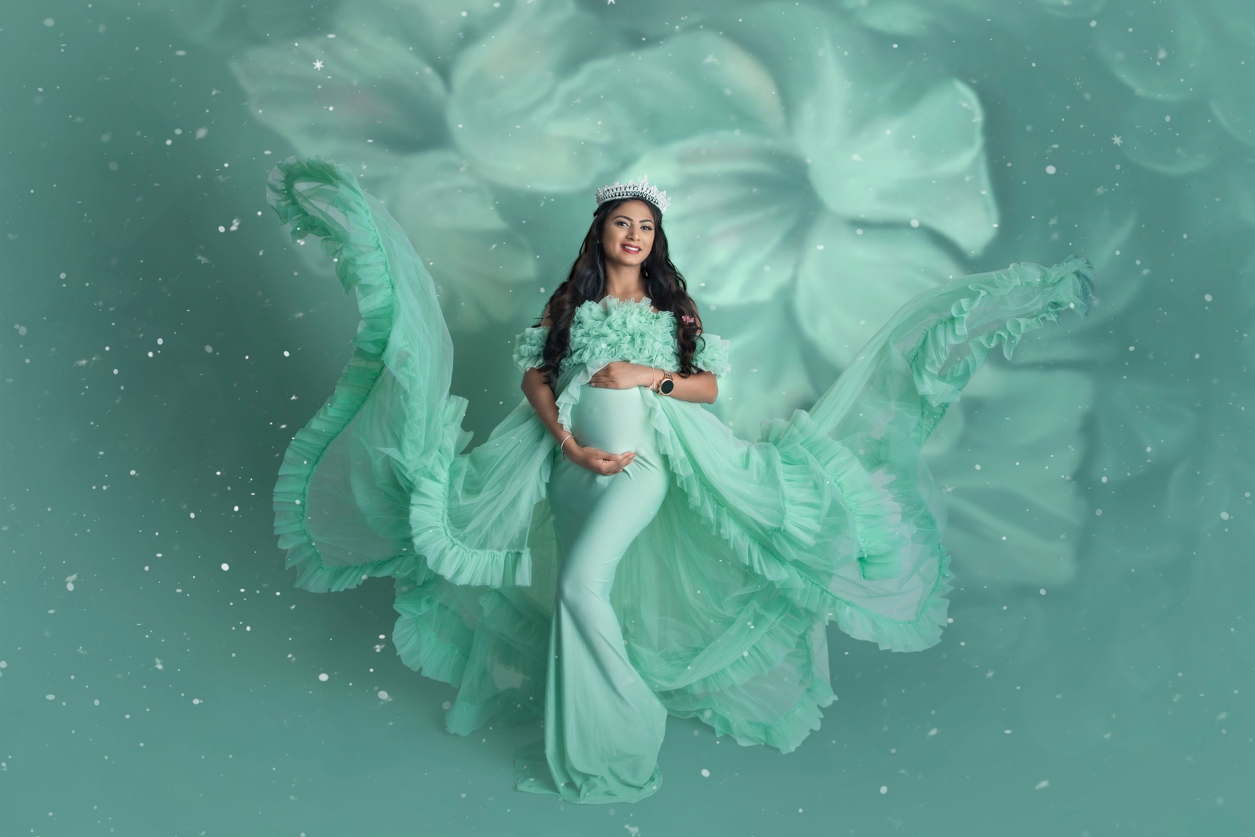 Ethereal maternity photo with flowing mint green fabric against dreamy aqua background.