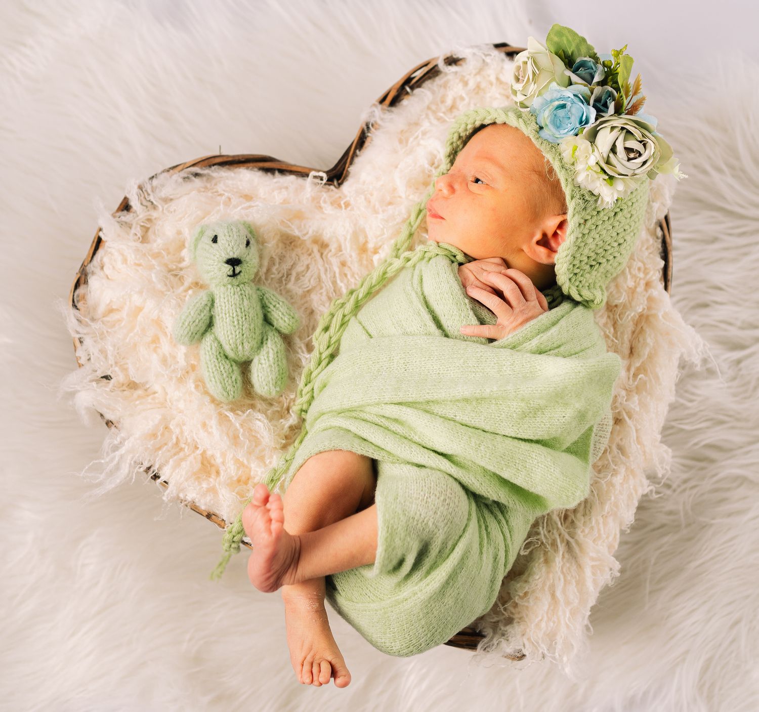 Neugeborenes Baby, das auf einem herzförmigen Bettchen liegt, liebevoll in einer zarten und harmonischen Szene arrangiert