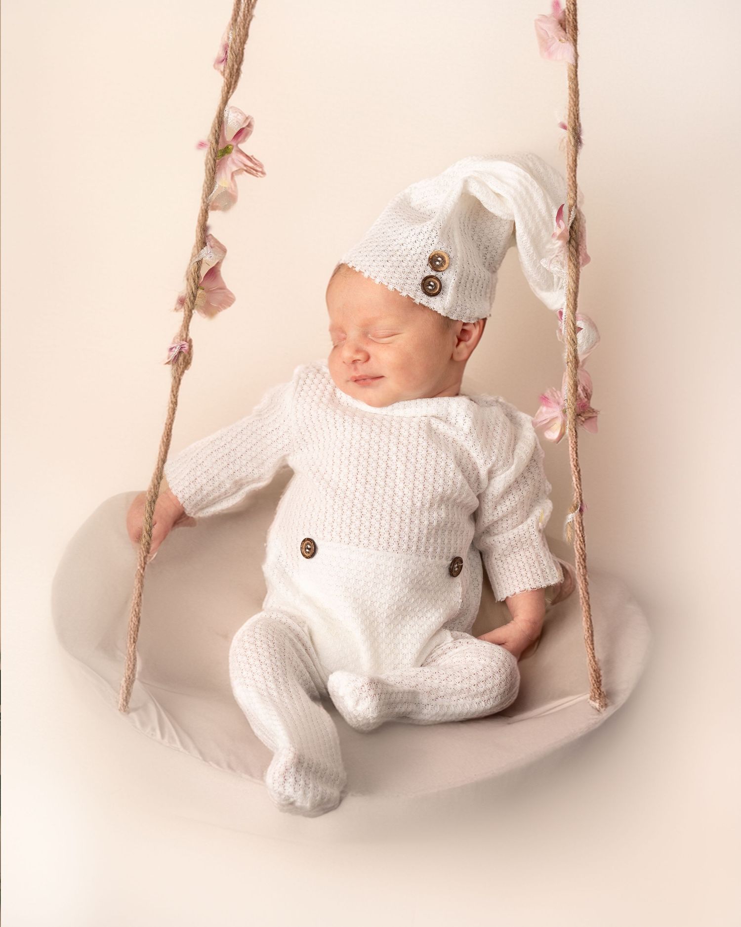 Neugeborenes Baby in einer kreativen Pose auf einer Schaukel, liebevoll und kunstvoll für ein einzigartiges Fotoshooting arrangiert