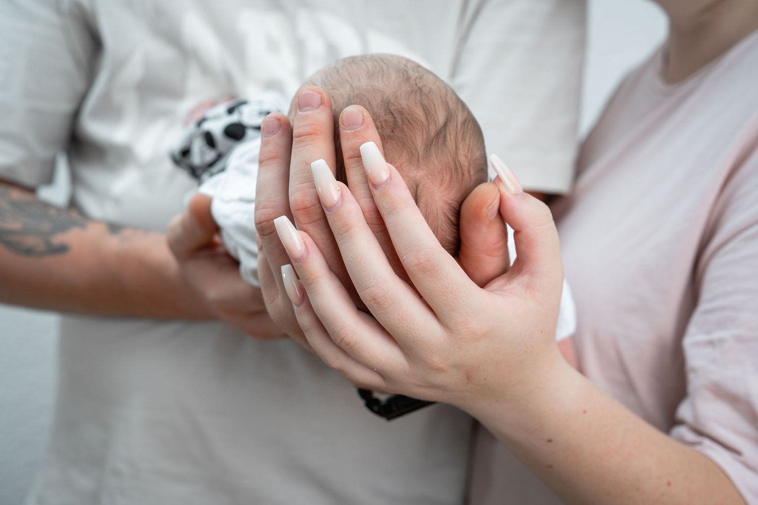 Neugeborenes Baby, liebevoll von den Händen der Eltern gehalten, aufgenommen in Ettlingen, symbolisiert Geborgenheit und Familie
