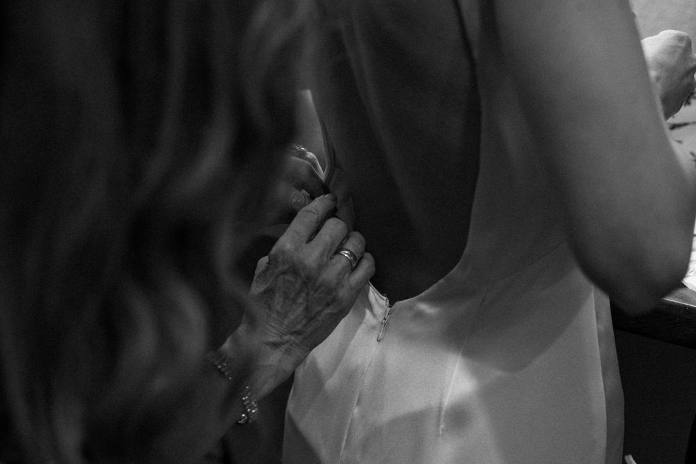 Close-up black and white shot of two hands connecting at an intimate moment during a wedding ceremony.