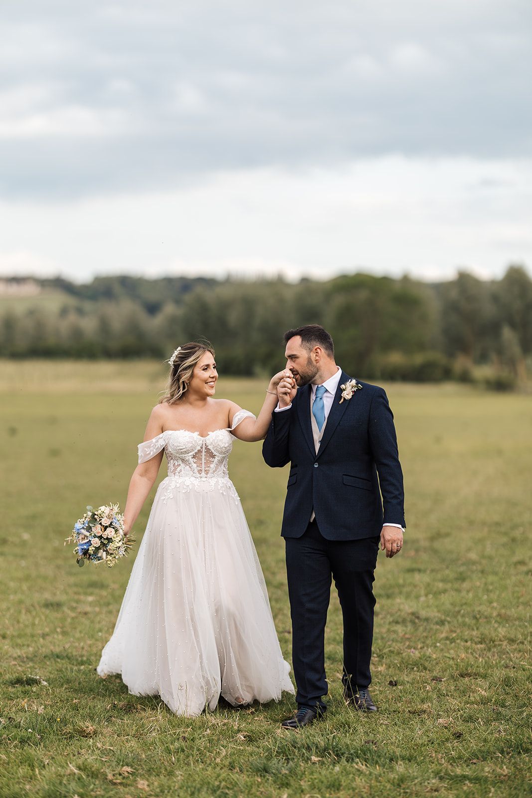 A newlywed couple shares a joyful moment together in a rural field on their wedding day.