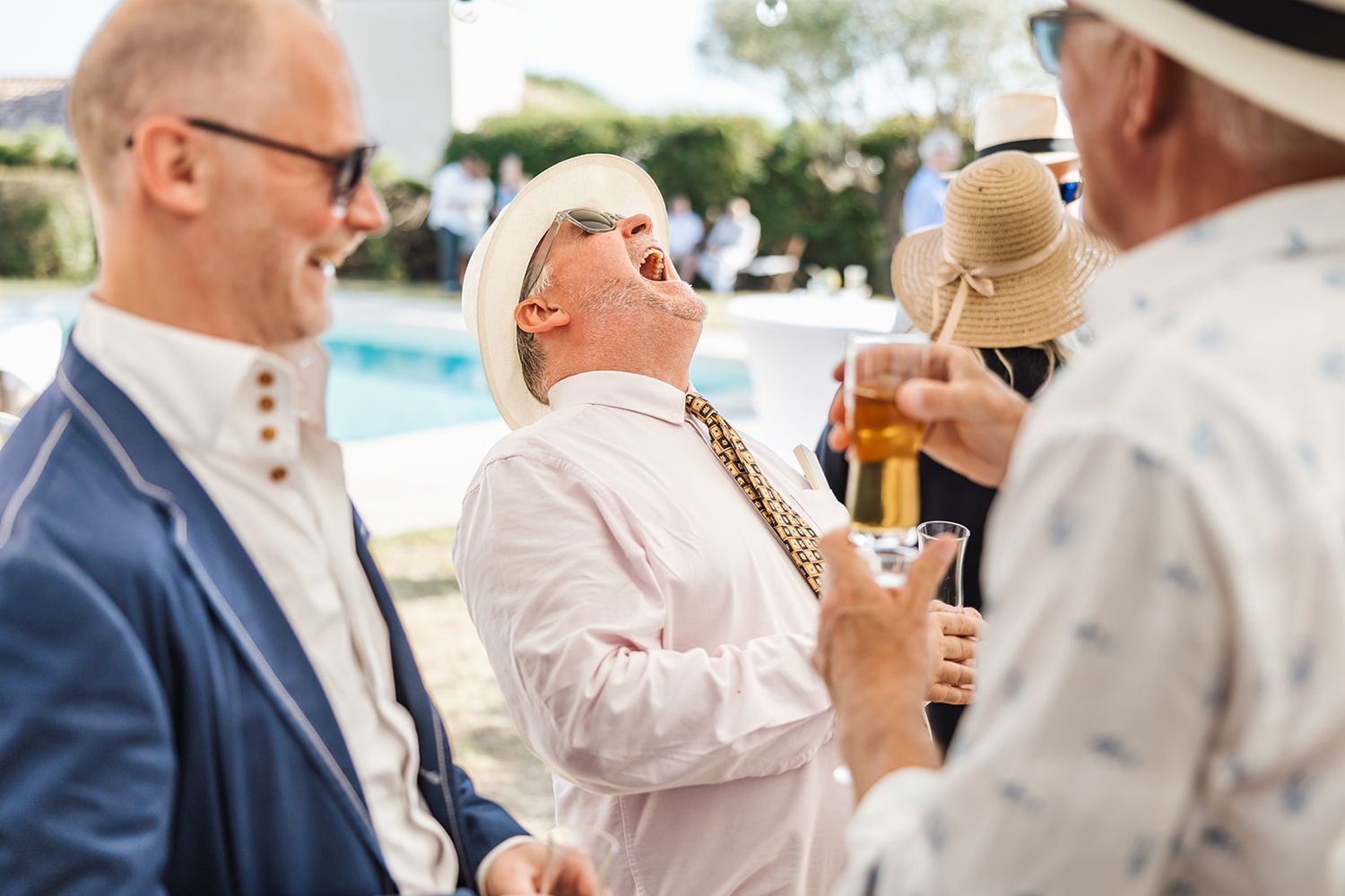 Well-dressed group enjoys cocktails at an outdoor party during a sunny afternoon social event.