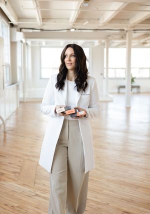 Medical Aesthetics Kelly Toldnes walking with boxes of product in a white lab coat during a headshot branding photography session in London