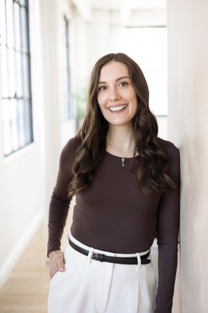 London Realtor Sachia Pepler Headshot photoshoot with captured by Thea photography. long brown hair with brown shirt and white dress pants.