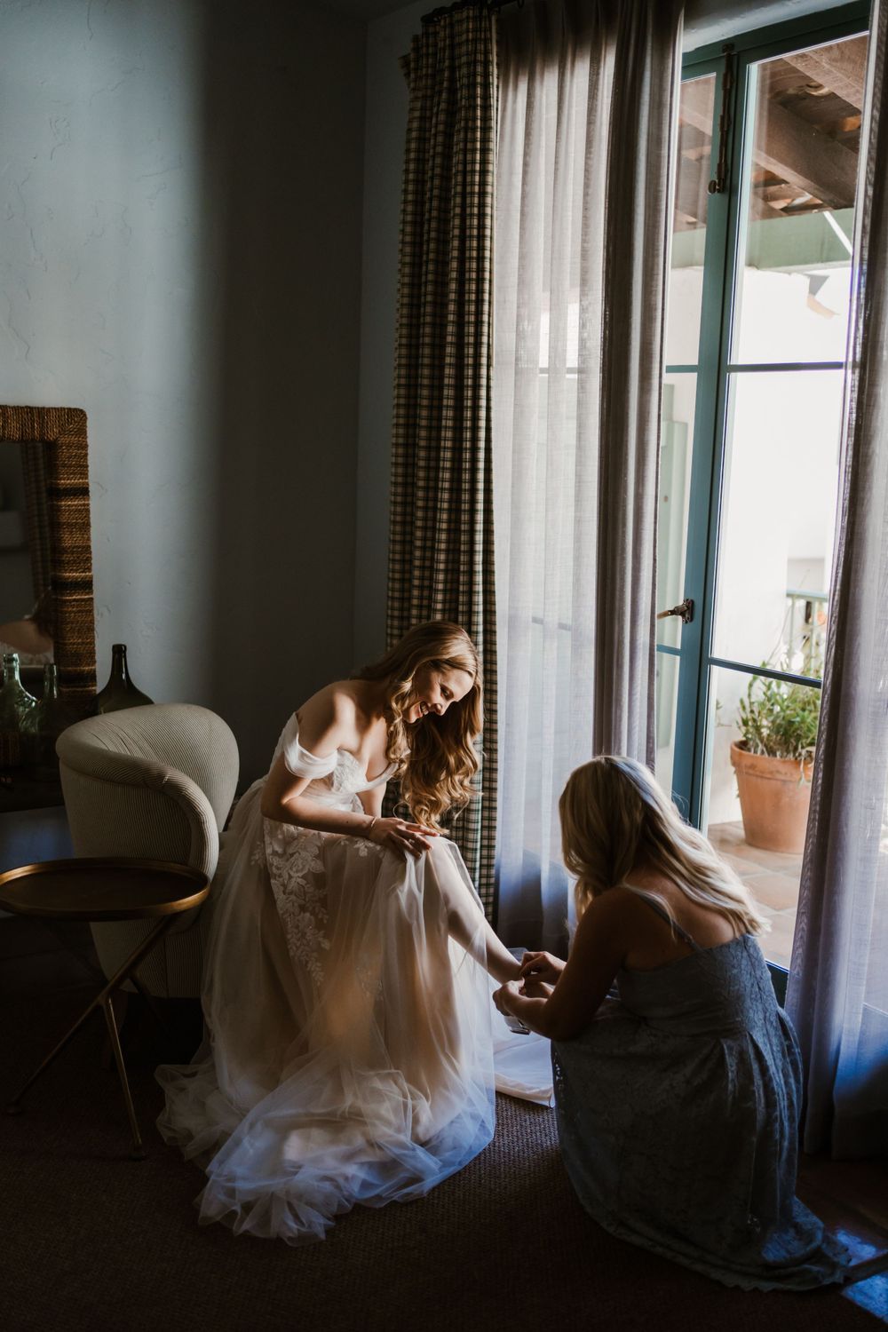 Wedding preparation scene with people in a sunlit room with checkered curtains.