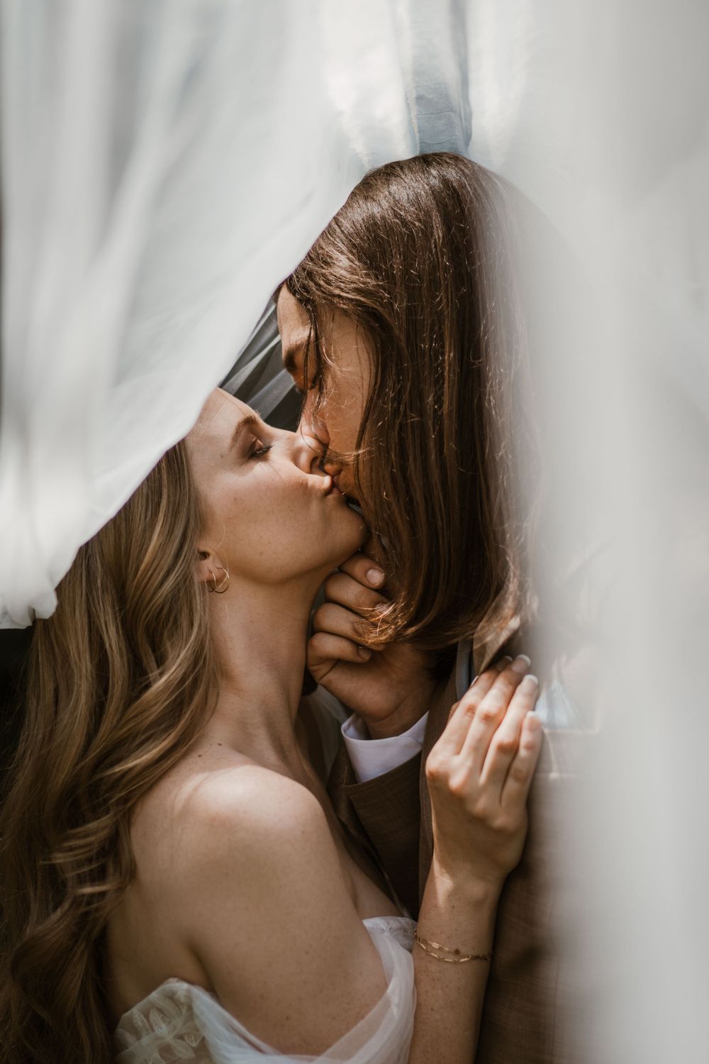 Artistic intimate portrait of a tender embrace between lovers near a sunlit window.
