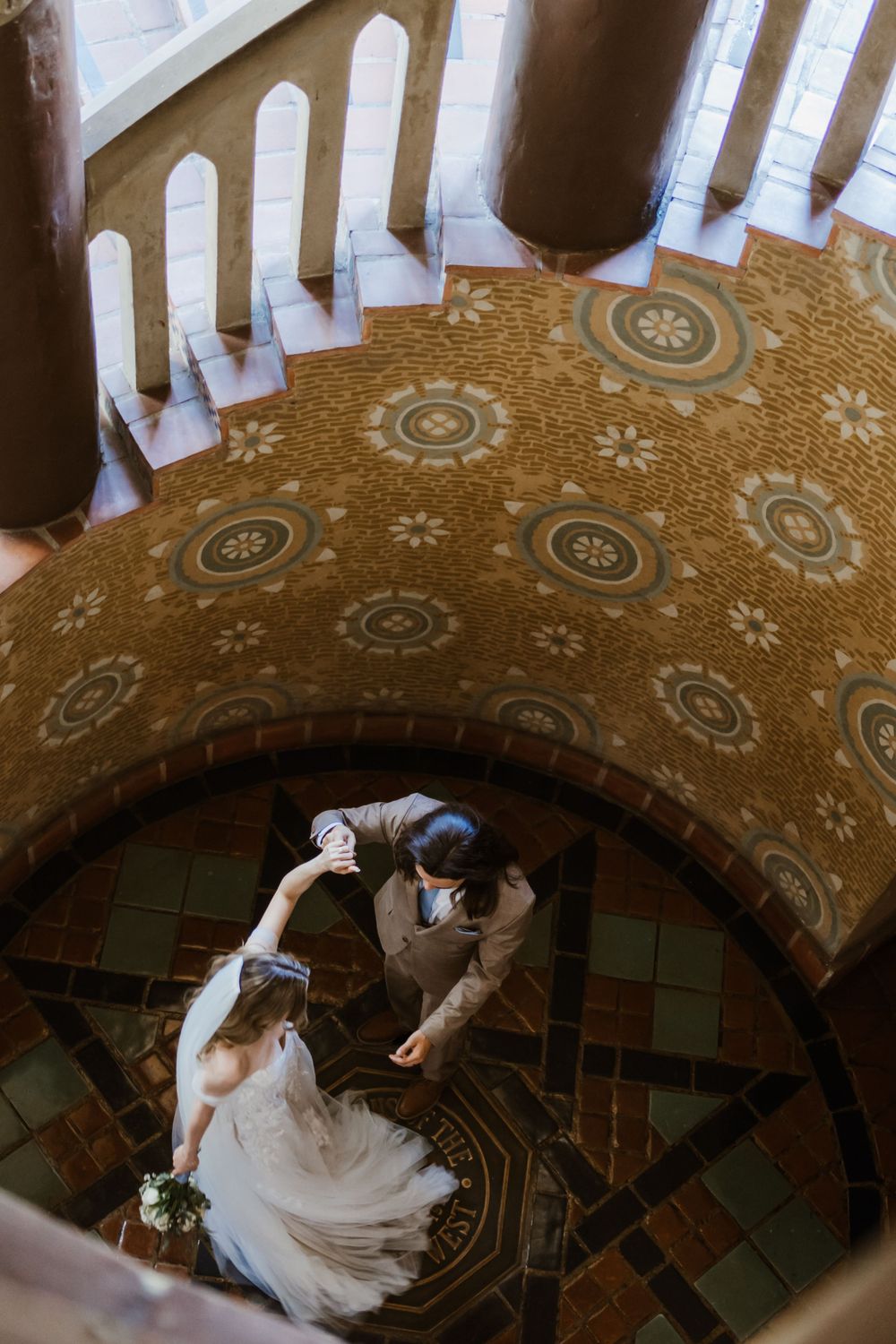 Two figures dancing in an arched interior with ornate gold patterned ceiling and white railings above.