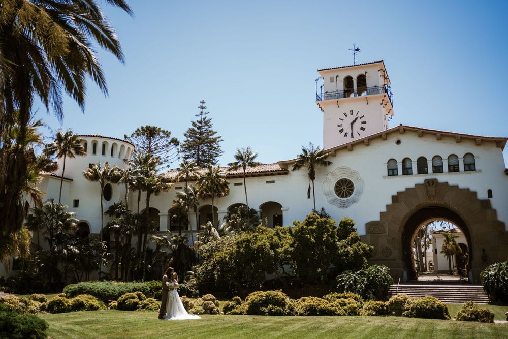 Spanish colonial-style courthouse building with white walls, clock tower and arched entrance surrounded by palm trees in Santa Barbara.