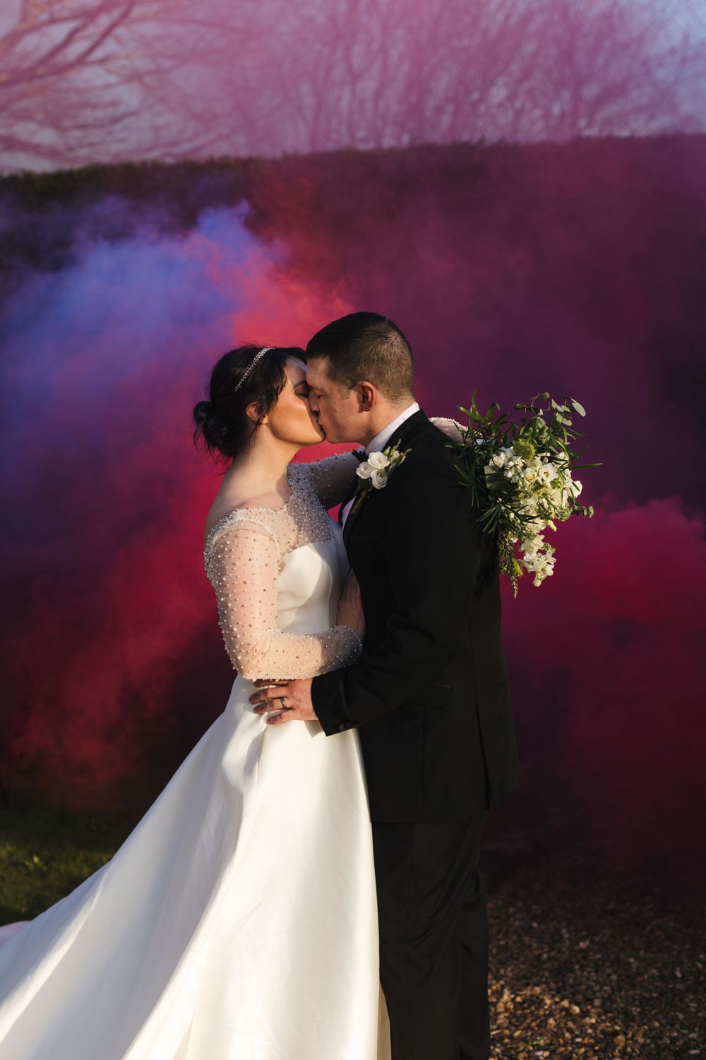 Dramatic wedding portrait with red and blue smoke effects in the background.
